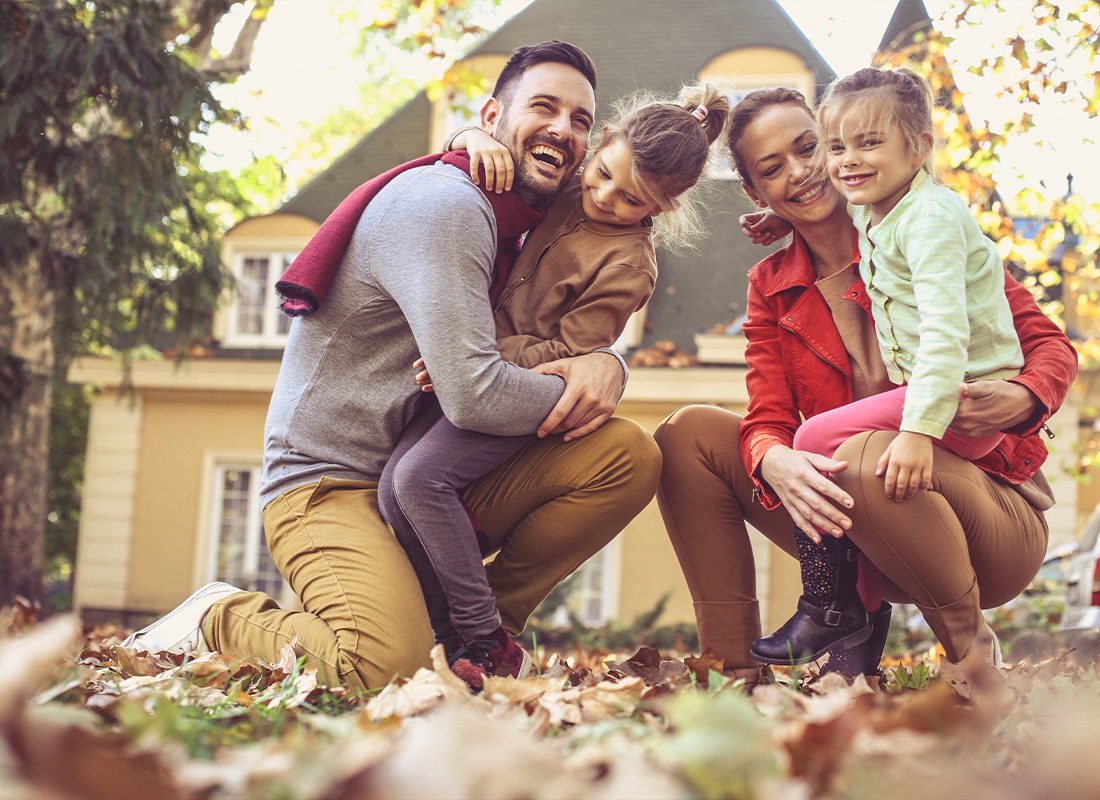 Insurance Solutions - A Family Playing in Their Front Yard While Wearing Sweaters and Scarves