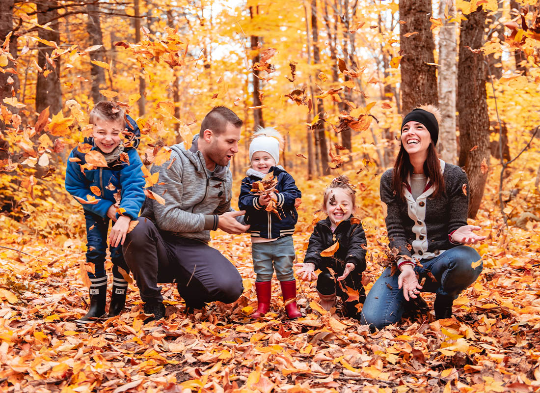 Personal Insurance - Happy Family Playing in Autumn Foliage While Wearing Hats and Sweaters